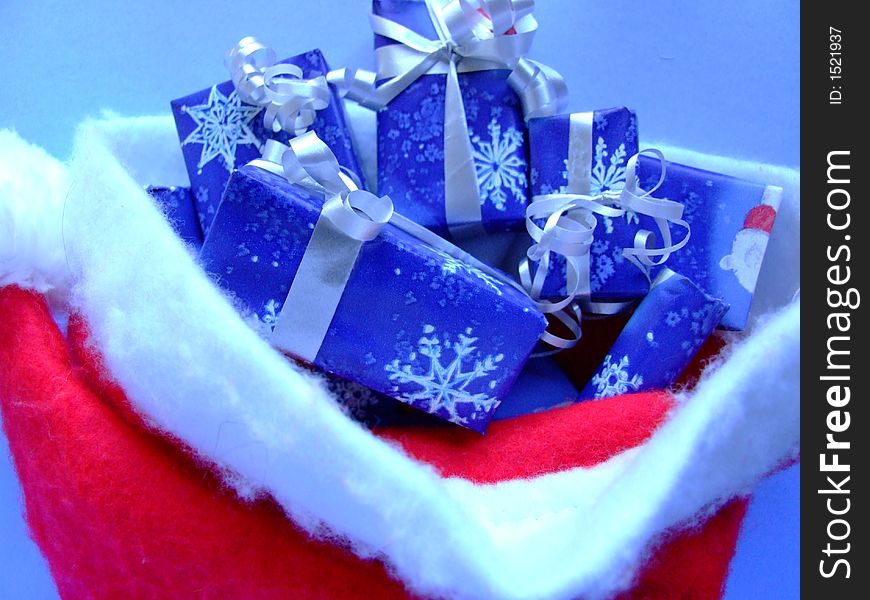 Santa's hat filled with Christmas gifts wrapped in white and blue. Santa's hat filled with Christmas gifts wrapped in white and blue