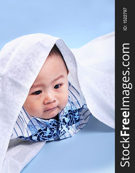 Cute baby boy with his blanket shot over blue background