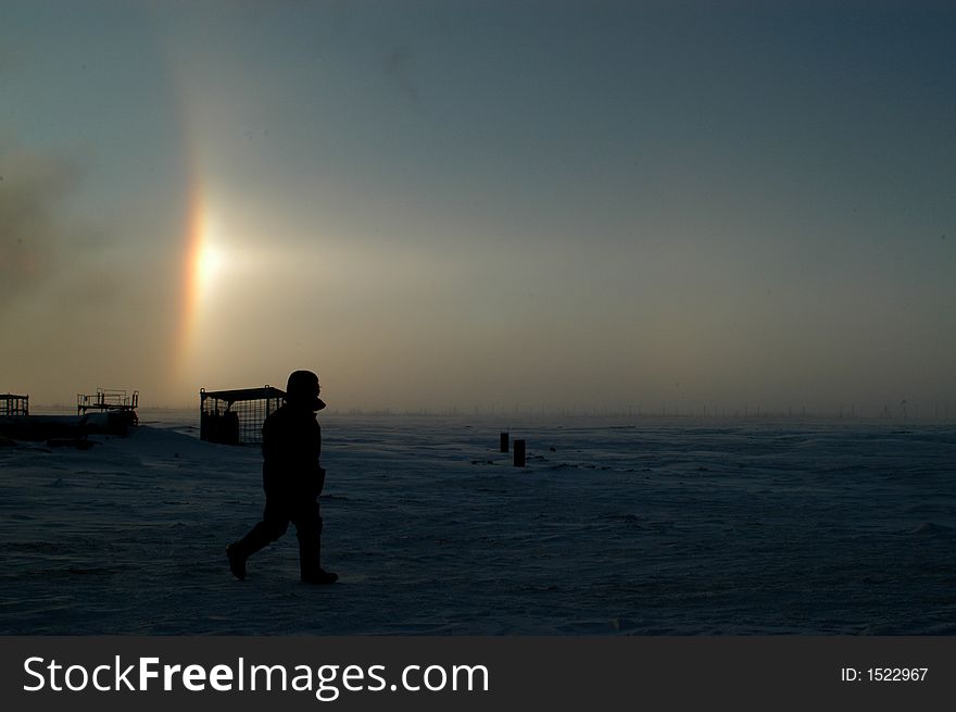 Gas field, winter, a worker walks to the construction site, a wonderful rainbow is on the background. Gas field, winter, a worker walks to the construction site, a wonderful rainbow is on the background.