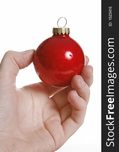 Hand holds up a shiny red christmas bulb. Hand holds up a shiny red christmas bulb