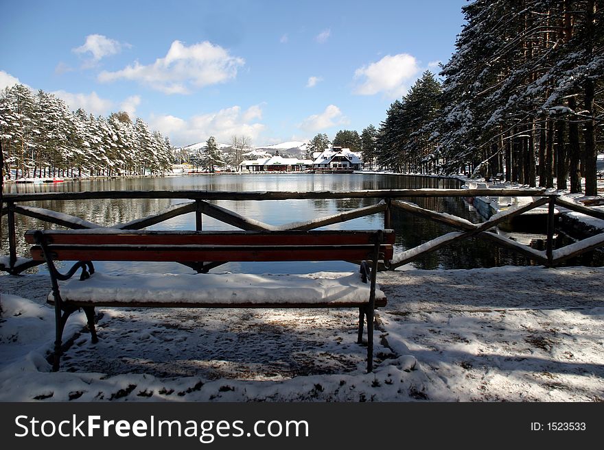 Sunny winter scene with snow and lake.