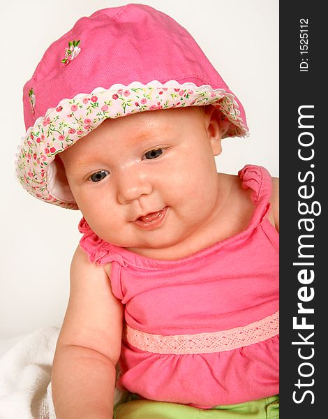 A baby girl sitting with a hat on her head. A baby girl sitting with a hat on her head