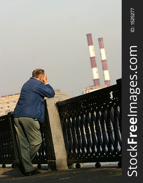 The man with the closed person costs on quay of the river. The man with the closed person costs on quay of the river