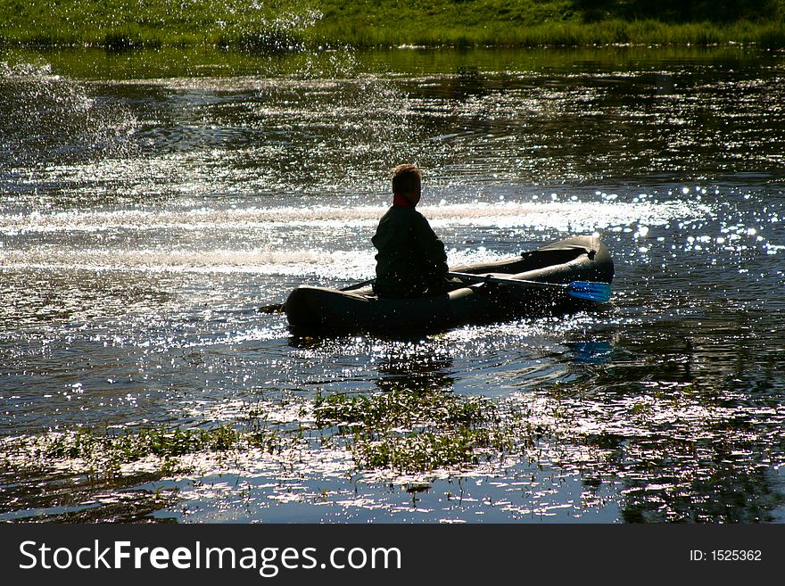 The person in a boat in water luminous on the sun. The person in a boat in water luminous on the sun