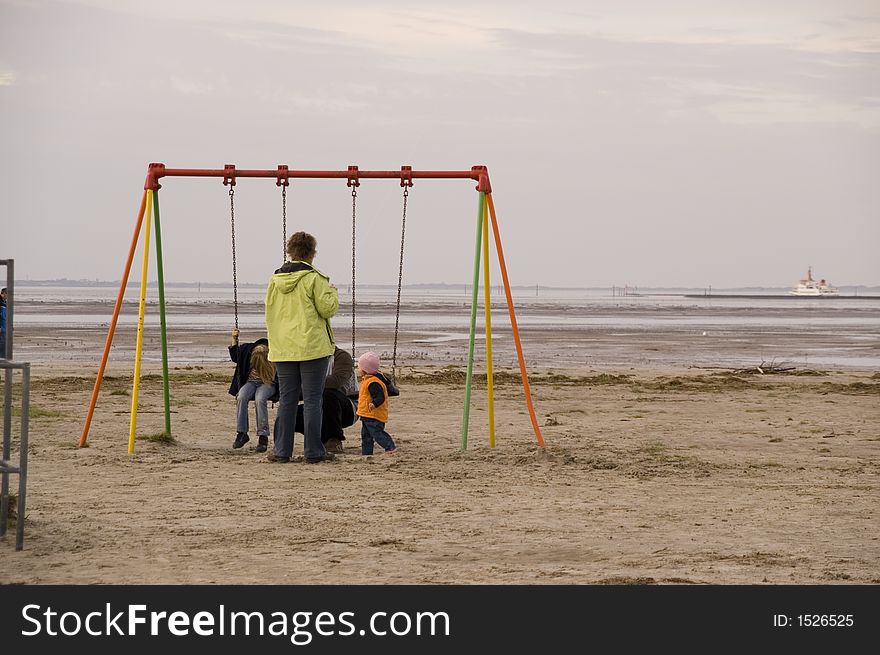 This picture shows a family with three children met at a seesaw. North Sea rushes in the background and the family enjoys the peaceful width and sees very relaxed out. This picture shows a family with three children met at a seesaw. North Sea rushes in the background and the family enjoys the peaceful width and sees very relaxed out.