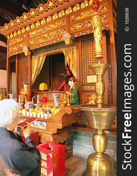 Woman worshipping Buddha in the City Temple in Shanghai, China. Woman worshipping Buddha in the City Temple in Shanghai, China.