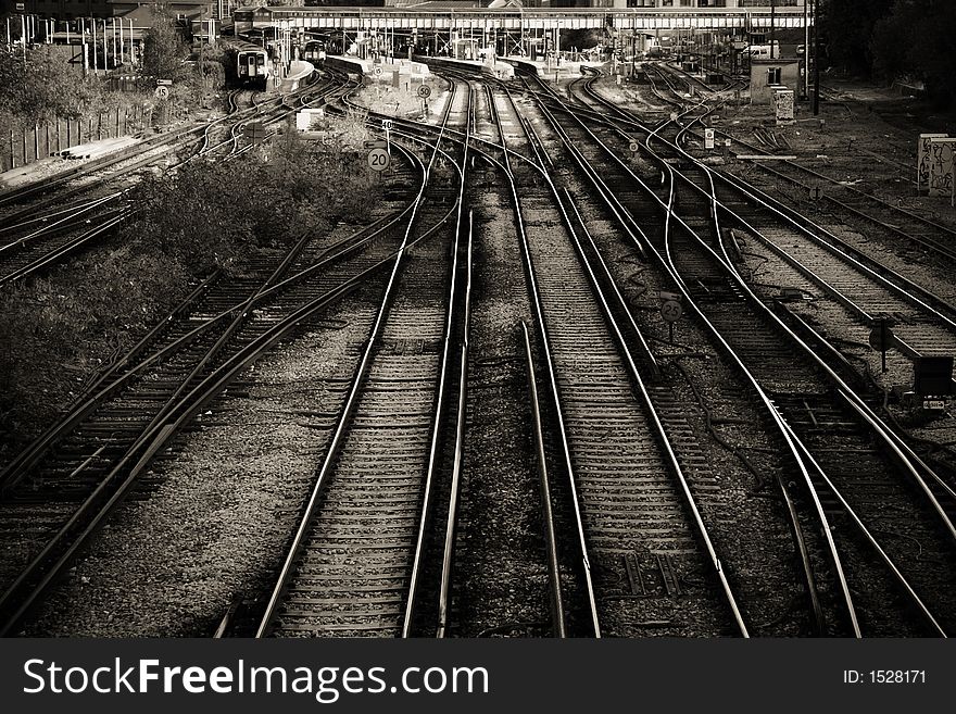 A view down on to a complex series of railway lines and junctions, leading in a major railway station in Guildford, UK. In sepia with subtle vignetting.