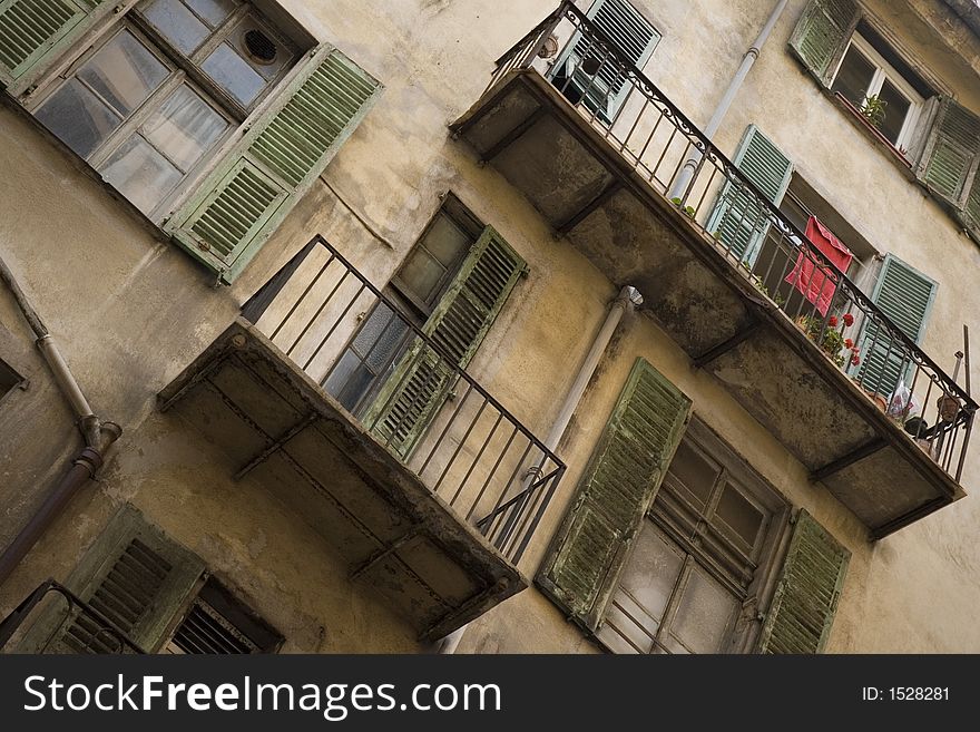 Looking up from the street at shuttered windows and balconies of a cream-coloured residential building in Old Nice, France. Washing is out to dry, plants are on display. Everything looks rather run down and in need of a clean or a fresh lick of paint. Looking up from the street at shuttered windows and balconies of a cream-coloured residential building in Old Nice, France. Washing is out to dry, plants are on display. Everything looks rather run down and in need of a clean or a fresh lick of paint.