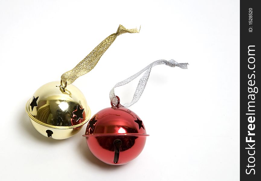 Golden and red little metal bells with stars punched in them for decorating a christmas tree, with sparkling ribbons attached to them. Isolated over white. Golden and red little metal bells with stars punched in them for decorating a christmas tree, with sparkling ribbons attached to them. Isolated over white