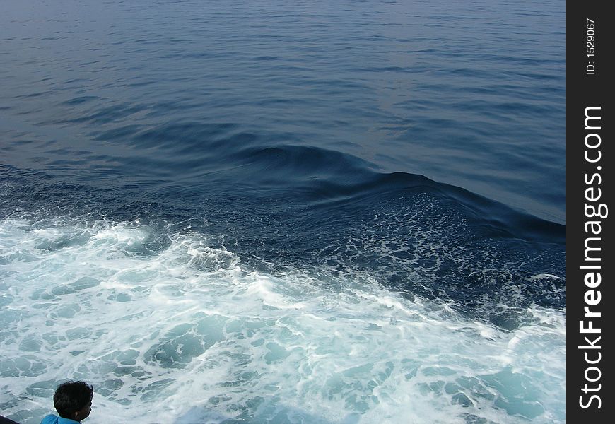 A man watching water trail left by a ship. A man watching water trail left by a ship