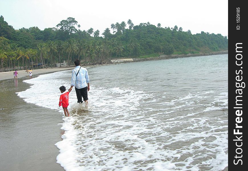 An image showing father and son strolling on a beach. An image showing father and son strolling on a beach