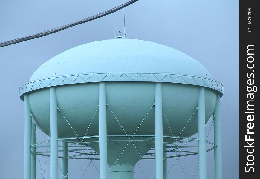 Large saucer shaped water tower against dark cloudy sky
