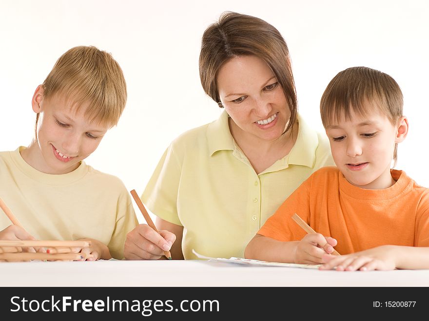 Young mother sitting at the table and draws with his sons. Young mother sitting at the table and draws with his sons