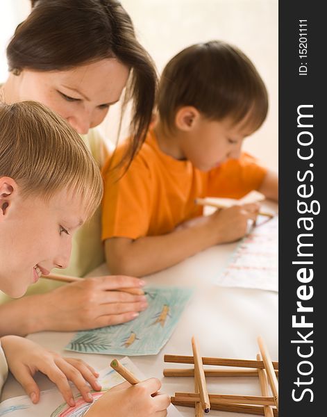 Young mother drawing at the table with her sons. Young mother drawing at the table with her sons