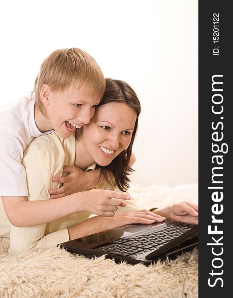 Happy mom and son lying with laptop