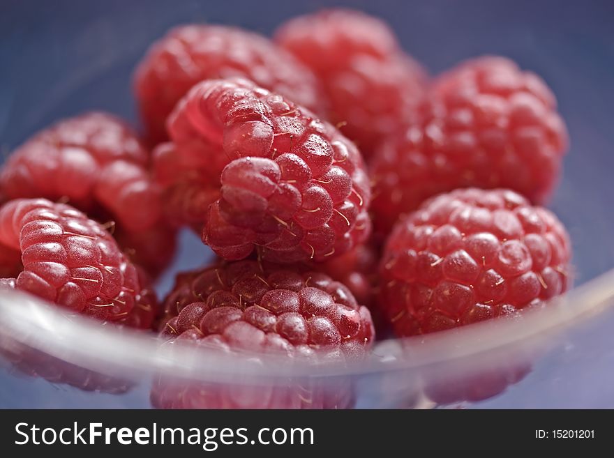 A a background image of freshly picked raspberries in a glass bowl. A a background image of freshly picked raspberries in a glass bowl