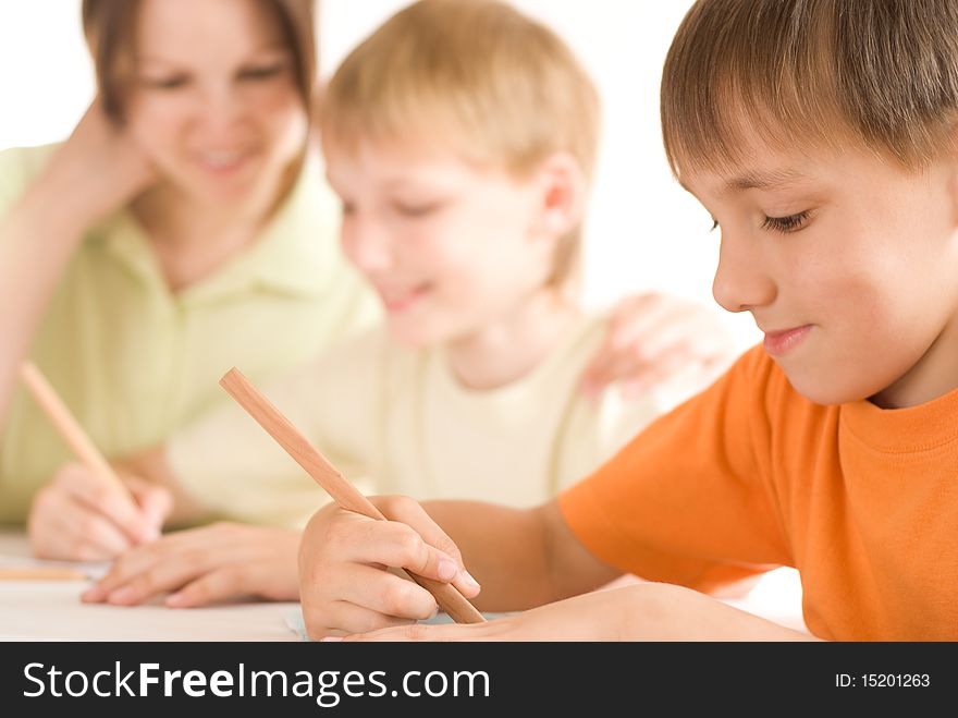 Mother sitting at the table and draws with his sons. Mother sitting at the table and draws with his sons