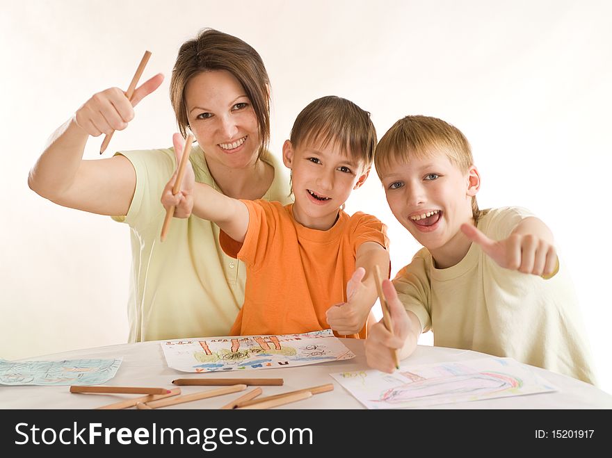 Young mother sitting at the table and draws with his sons. Young mother sitting at the table and draws with his sons