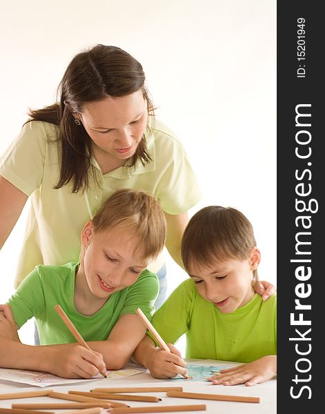 Mother staying at the table and draws with his sons. Mother staying at the table and draws with his sons