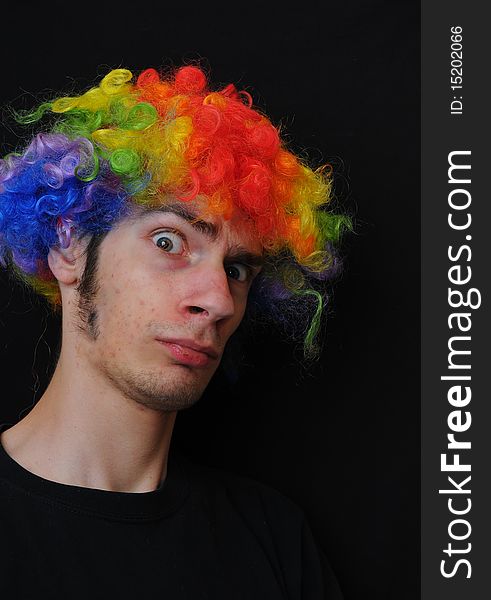 A silly crazy man wearing a clown wig with rainbow colors staring at the camera with a serious look. A silly crazy man wearing a clown wig with rainbow colors staring at the camera with a serious look.