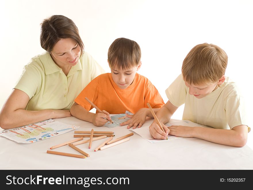 Young mother sitting at the table and draws with his sons. Young mother sitting at the table and draws with his sons