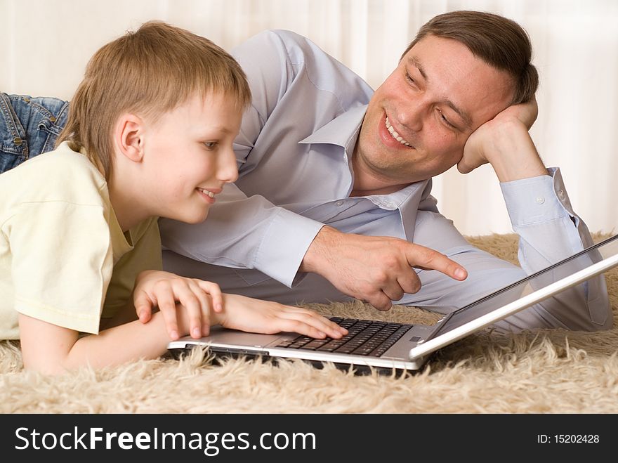 Happy father and son lying with laptop