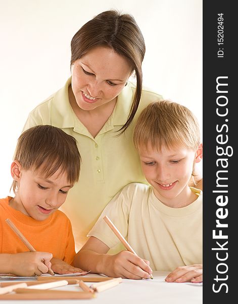 Young mother sitting at the table and draws with sons. Young mother sitting at the table and draws with sons