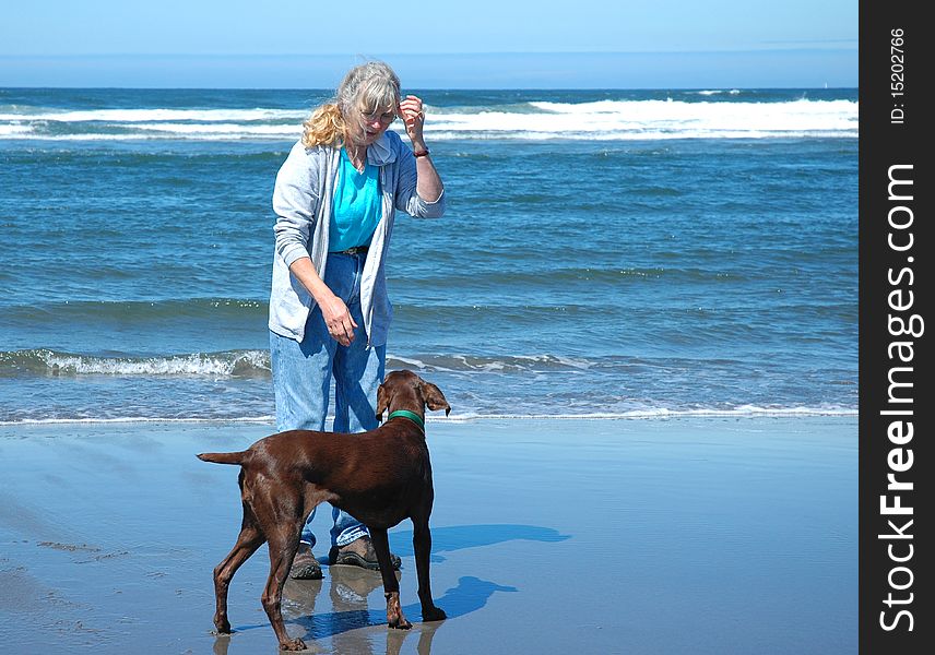 An active senior woman playing with her dog at Long Beach Washington