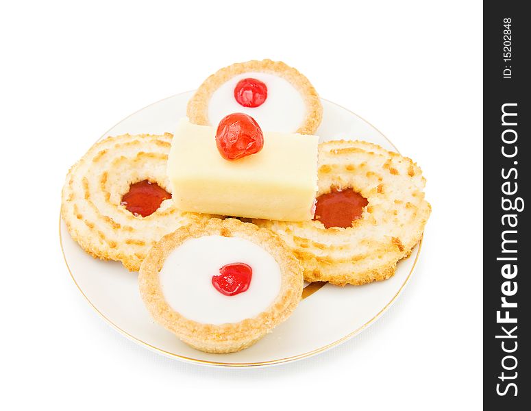 Coconut and jam biscuits with slice of cake and cherry on top. Isolated over white background. Coconut and jam biscuits with slice of cake and cherry on top. Isolated over white background.