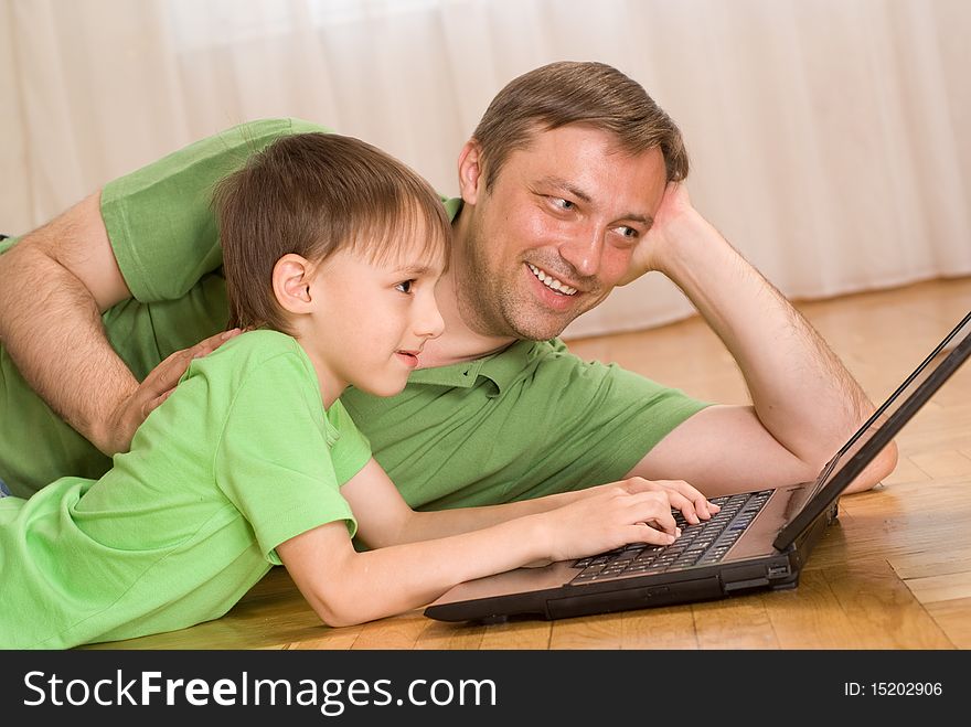 Father and son lying on the carpet with laptop. Father and son lying on the carpet with laptop