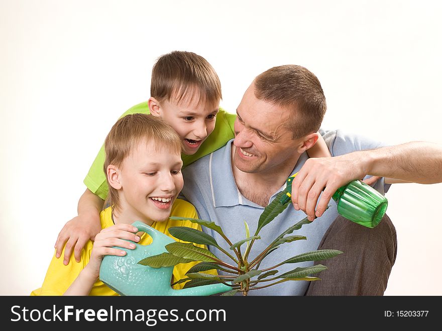 Father and children sitting on the carpet and watering flower. Father and children sitting on the carpet and watering flower