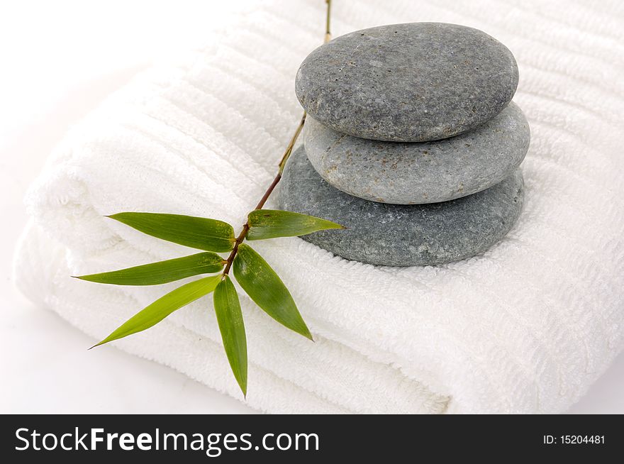 bath towel and three stones balanced with lucky bamboo on white. bath towel and three stones balanced with lucky bamboo on white