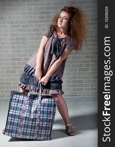 Tired redhaired woman with shopping bag. brick wall as background.