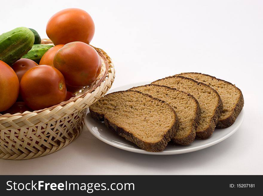 Tomatoes and cucumbers in a plate of rice straw and bread on a plate on a white background. Tomatoes and cucumbers in a plate of rice straw and bread on a plate on a white background