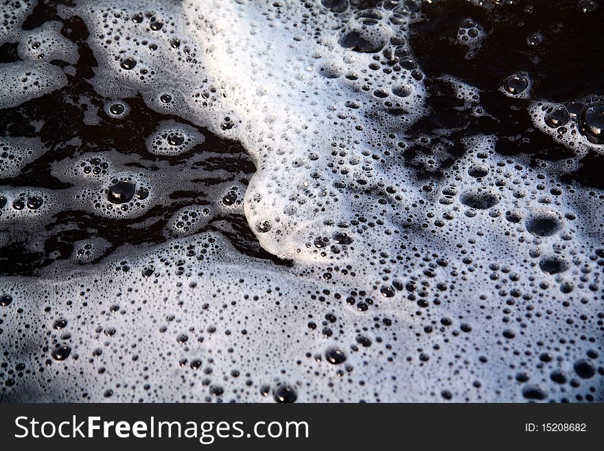 White spume on black surface water