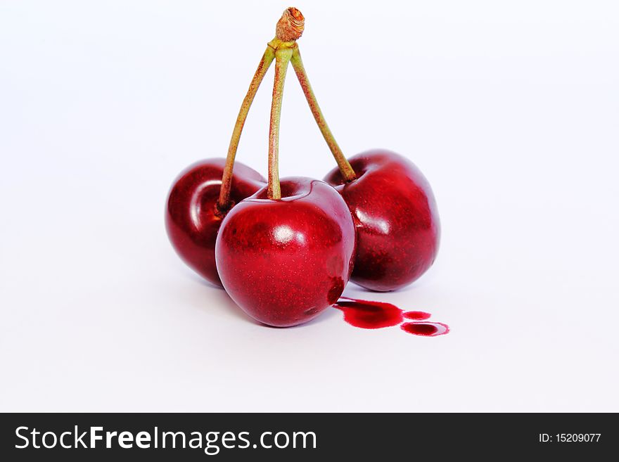 Three delicious cherries with a squirt of juice. Three delicious cherries with a squirt of juice
