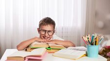 Joyful Little Boy Sitting At The Table With Pencils And Textbooks. Happy Child Pupil Doing Homework At The Table Stock Images