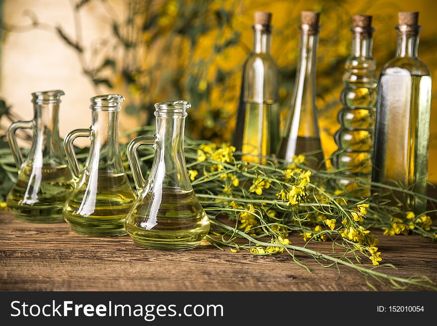 Rapeseed flowers and rapeseed oil in a bottle on the table.