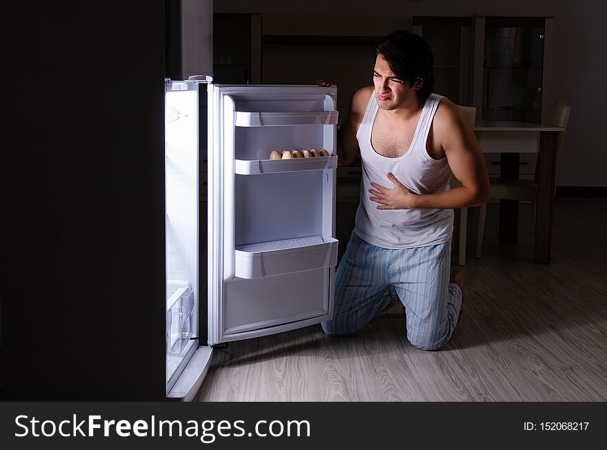 The man breaking diet at night near fridge