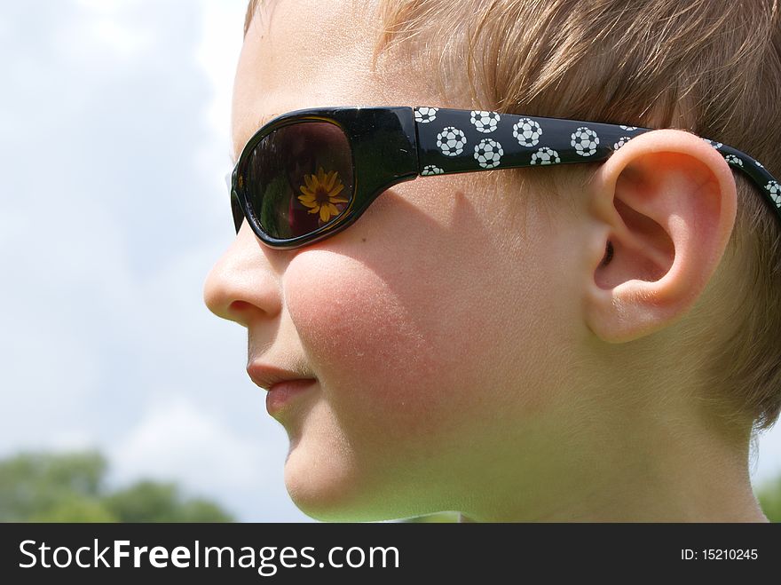 A boy in a  and glasses from the sun, thinking. A boy in a  and glasses from the sun, thinking