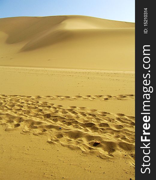 Foot steps on the dune under blue sky