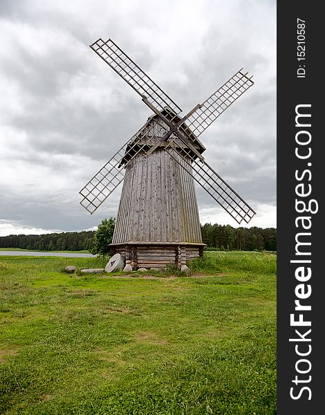 Old windmill on a meadow against cloudy sky