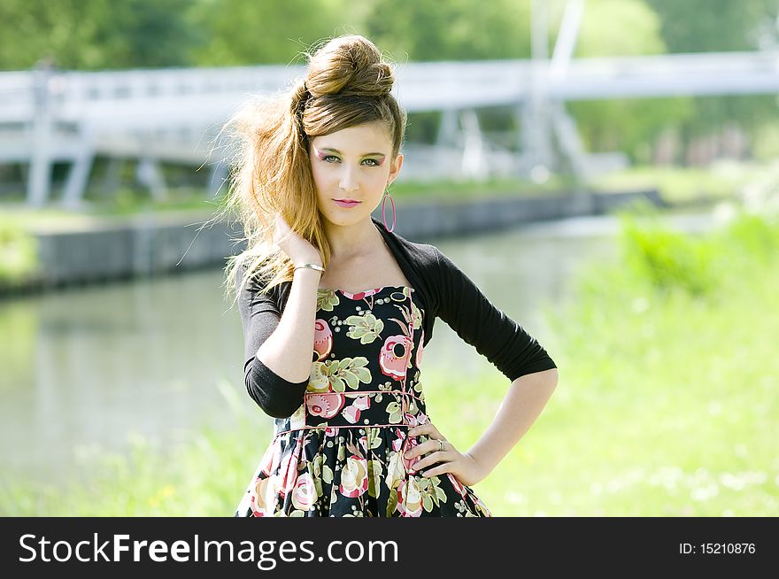 Teenager girl model presenting clothes in the park near the water and a bridge