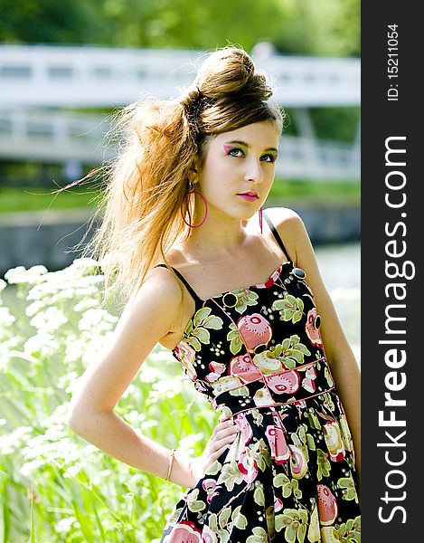 Teenager girl model presenting clothes in the park near the water and a bridge