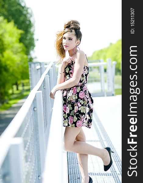 Teenager girl model presenting clothes in the park near the water and a bridge