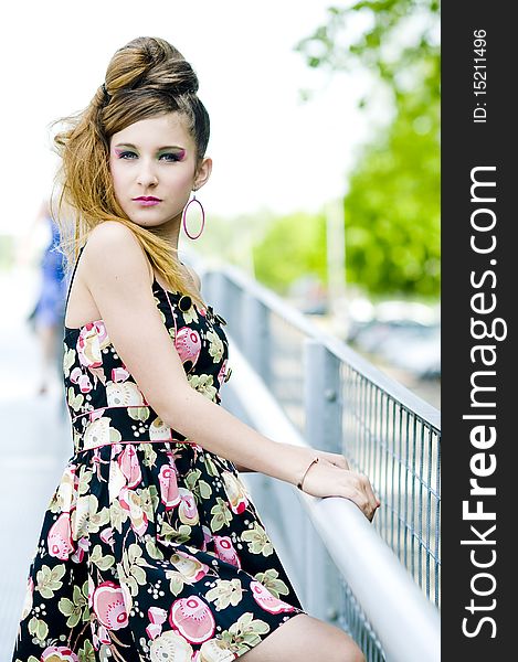 Teenager girl model presenting clothes on a bridge in the parc, light natural background. Teenager girl model presenting clothes on a bridge in the parc, light natural background