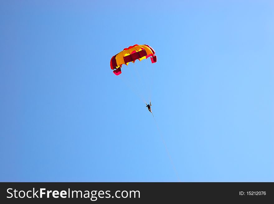 Man with a parachute in the blue sky