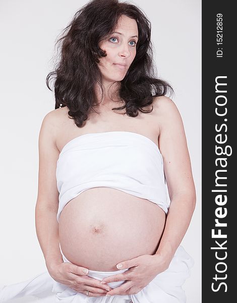 Studio portrait of pregnant dreamy woman holding her belly