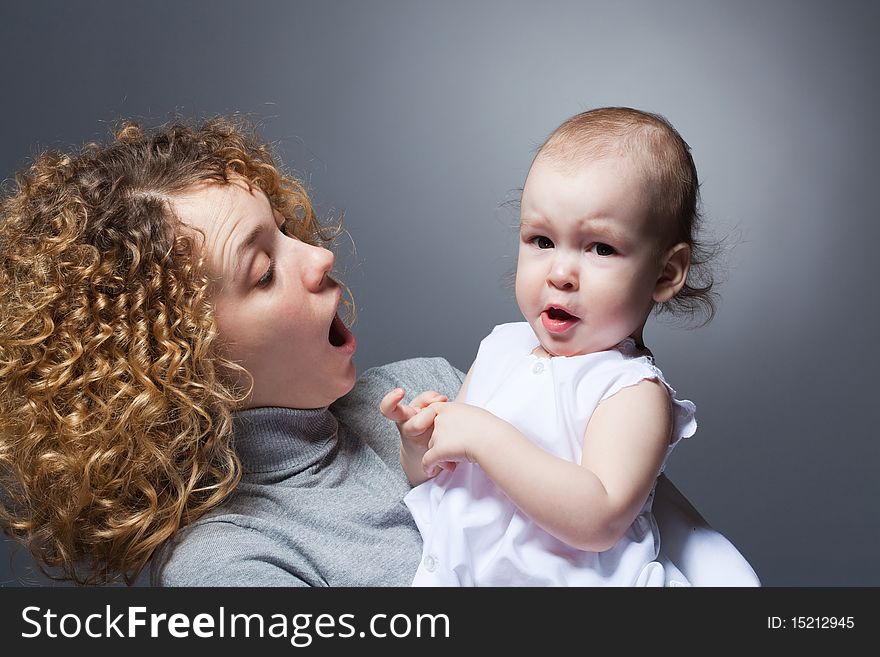 Young beautiful curly mother holding cute upset baby