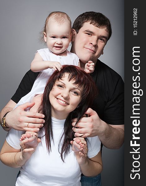 Closeup family portrait of young loving couple with cute baby on mother's shoulders. Closeup family portrait of young loving couple with cute baby on mother's shoulders